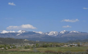 Snow-capped mountains above a green valley in Colorado, showcasing Rocky Mountain Commercial Real Estate properties.